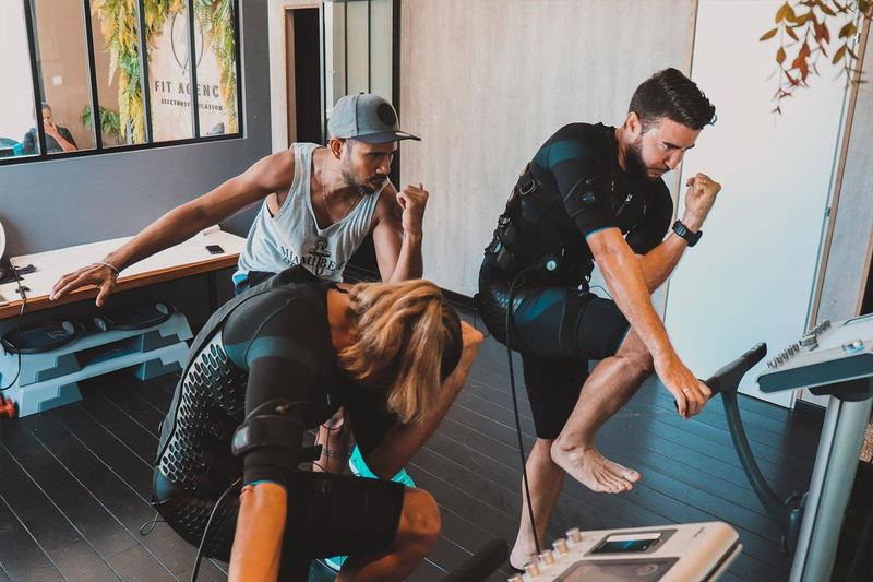 Un coach corrige la posture de deux clients pendant une séance en duo